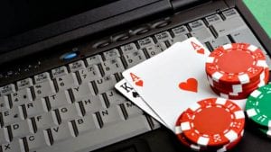 a laptop keyboard with poker chips and cards next to it