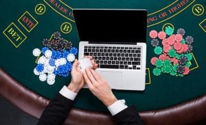 a laptop on a casino table with poker chips next to it
