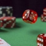 a red dice ebing thrown at a green casino table