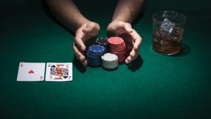 hands hoplding poker chips on a casino green table