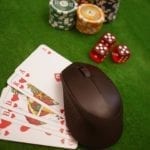 a green poker table with cards, cubes and poker chips and a computer mouse on the cards