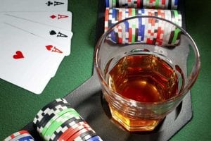 whiskey, poker cards and chips on a green poker table